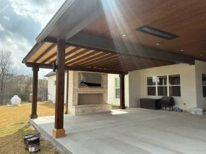 Modern luxury patio with wooden pergola and outdoor entertainment area featuring fireplace