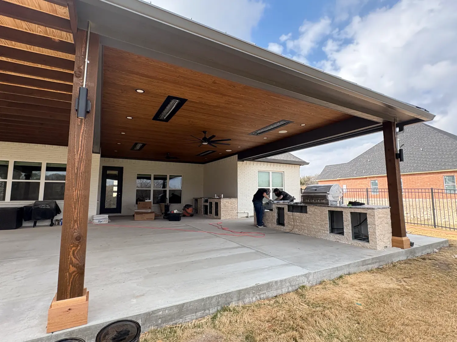 Luxury outdoor entertainment area with wood pergola, built-in grill, and concrete patio in Fort Worth