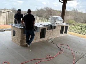 Contractors installing custom outdoor kitchen in luxury backyard entertaining space with scenic views