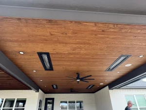 Modern covered patio with wooden ceiling, outdoor heaters, and ceiling fan for luxury outdoor living spaces