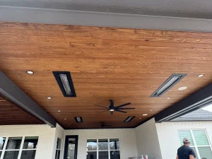 Modern luxury patio ceiling with wood planks, integrated heaters, and ceiling fan for outdoor entertaining