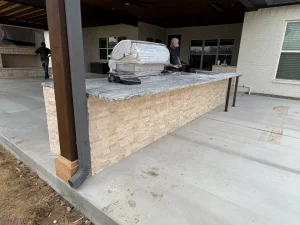 Luxury outdoor entertainment area under construction featuring granite-topped bar and stone base in Fort Worth