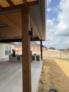 Luxury backyard patio under construction featuring wooden pergola and metal railings in Fort Worth