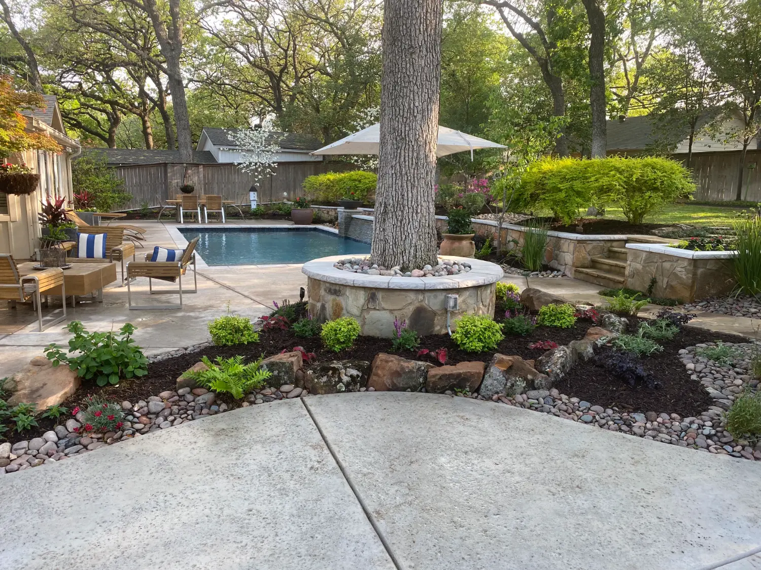 Luxury backyard transformation featuring custom pool, stone fire pit, and sophisticated patio entertainment area in Fort Worth