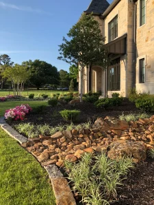 Luxury residential backyard with custom patio design, rock landscaping, and flowering gardens in Fort Worth