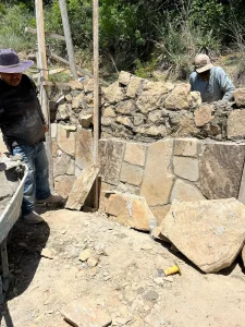 Skilled workers constructing custom stone retaining wall for luxury outdoor living space in Fort Worth