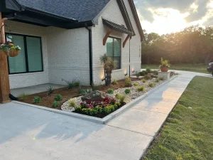 Modern white brick home with luxury landscape design featuring manicured flower beds and stone walkway