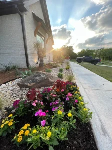 Luxury landscape design featuring vibrant flower beds and stone accents along residential driveway