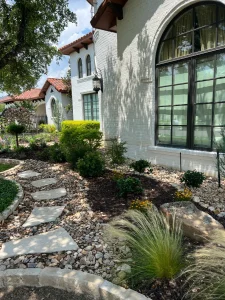Luxury landscape design with stone pathway, ornamental grasses, and contemporary white brick home exterior