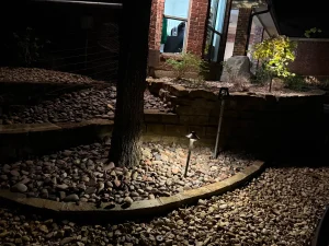 Luxury landscape design featuring illuminated river rock hardscape and specimen tree in Fort Worth outdoor living space