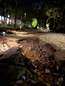 Illuminated riverbed stone pathway in luxury outdoor living space at night