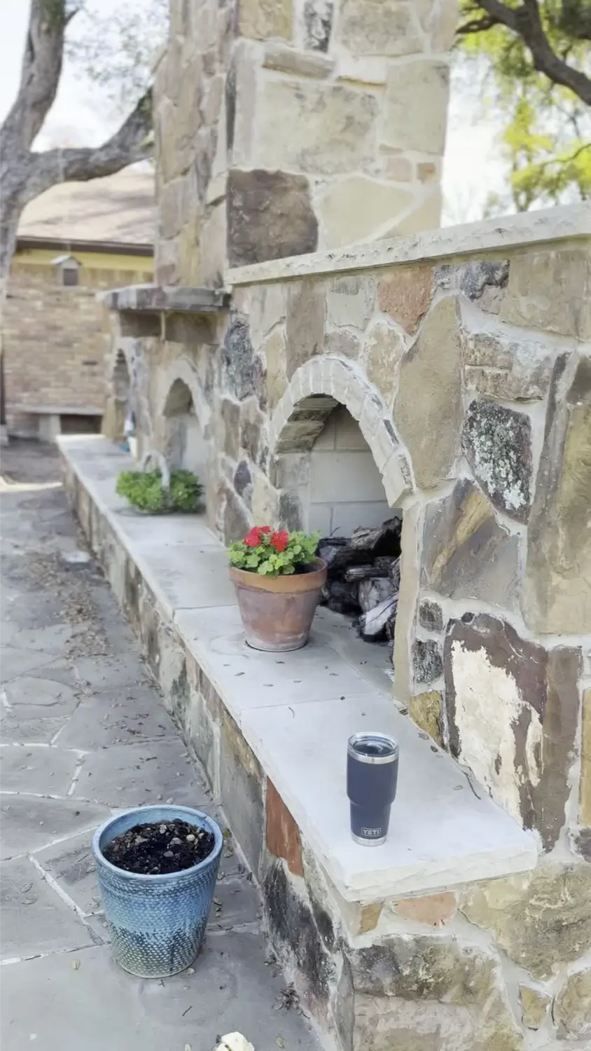 Luxury outdoor living space featuring stone architectural niche with potted flowers and modern accessories