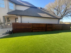 Modern luxury backyard transformation with artificial turf and horizontal wood privacy fence