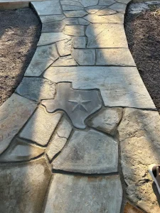 Custom stone patio with Texas-shaped accent tile in luxury outdoor living design